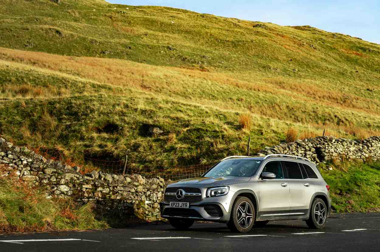 A modern silver SUV driving on a safe, open coastal road during daytime representing automotive security and freedom